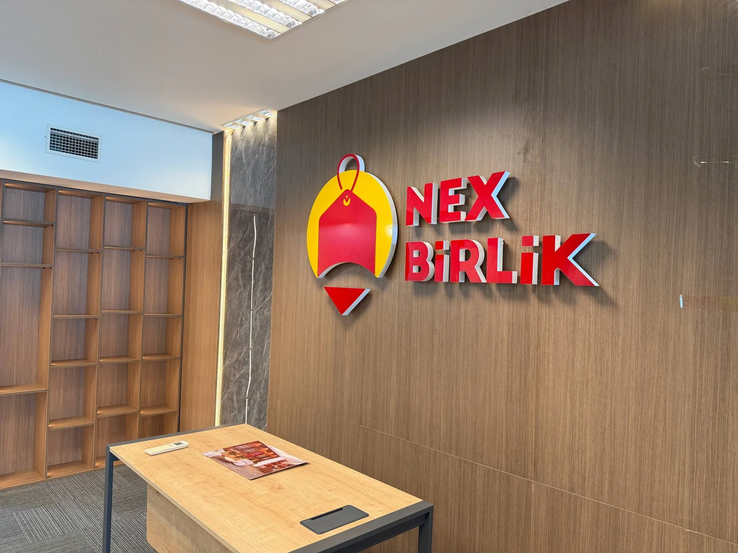 NexBirlik logosu ve masa bulunan boş karşılama alanı